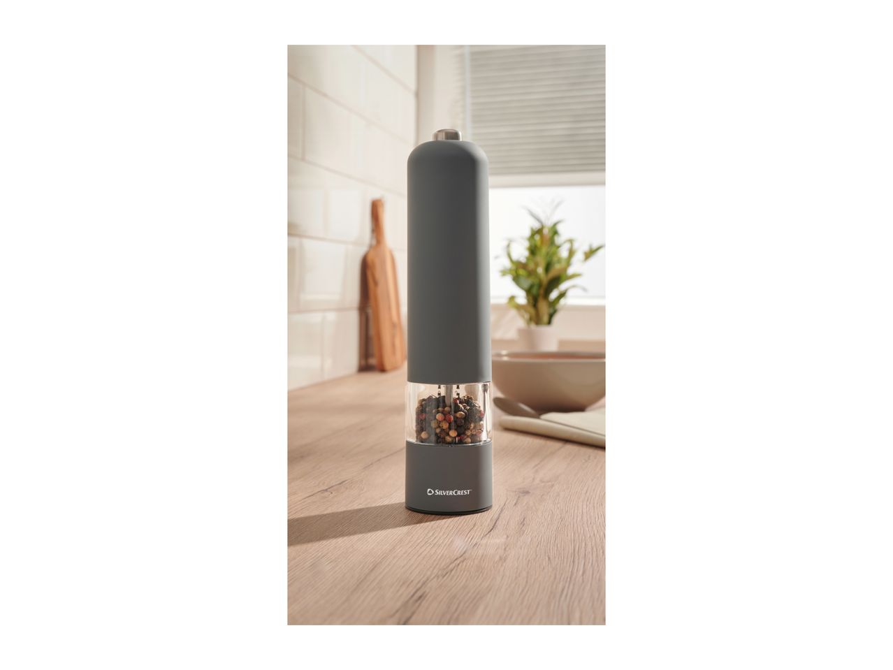A SilverCrest electric pepper grinder filled with peppercorns on a wooden kitchen counter.