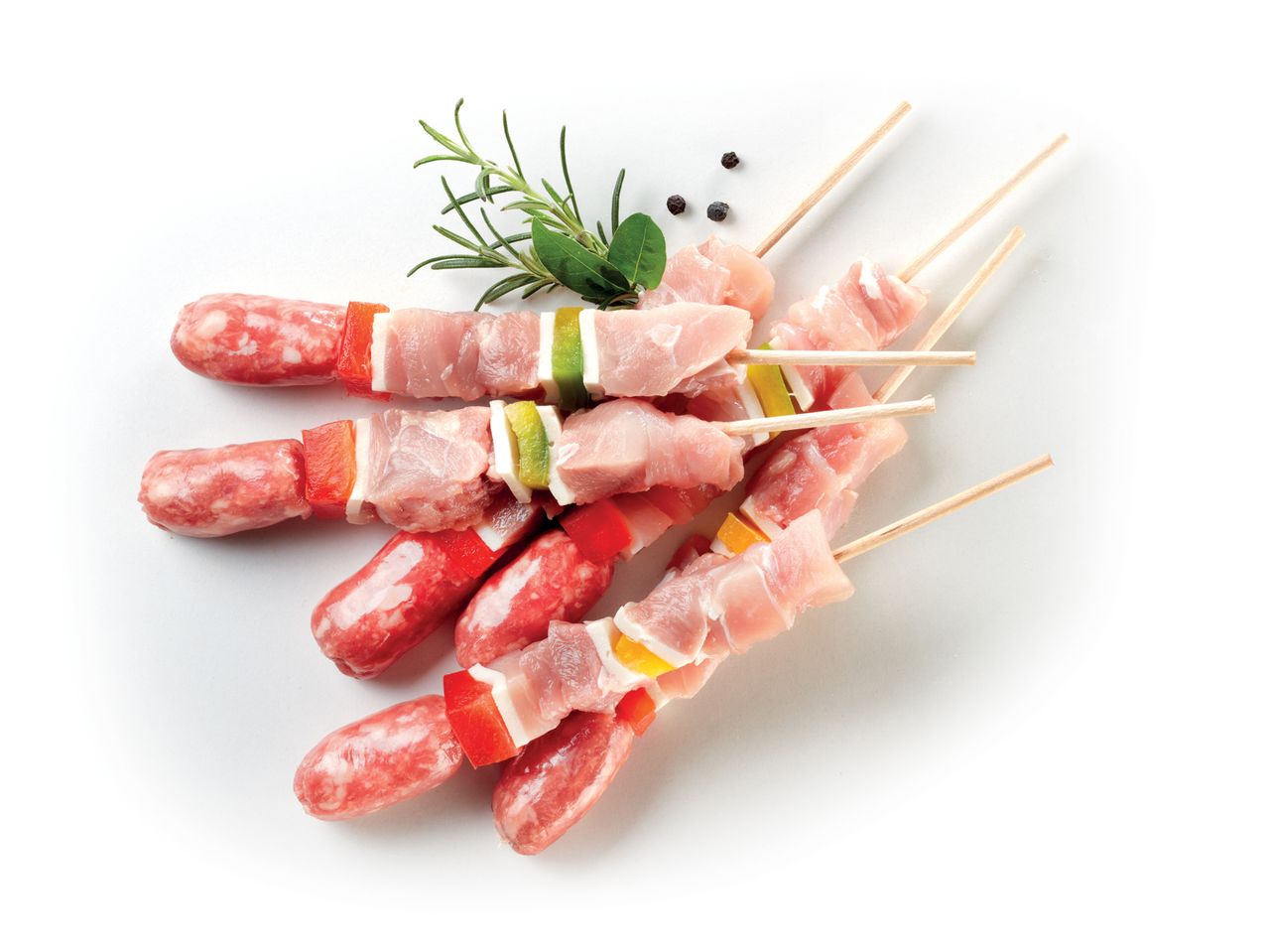 Spiedini di pollo e salsiccia crudi con verdure, pronti per la griglia.