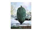 Green winter protection fleece cover on a plant in a snowy garden.