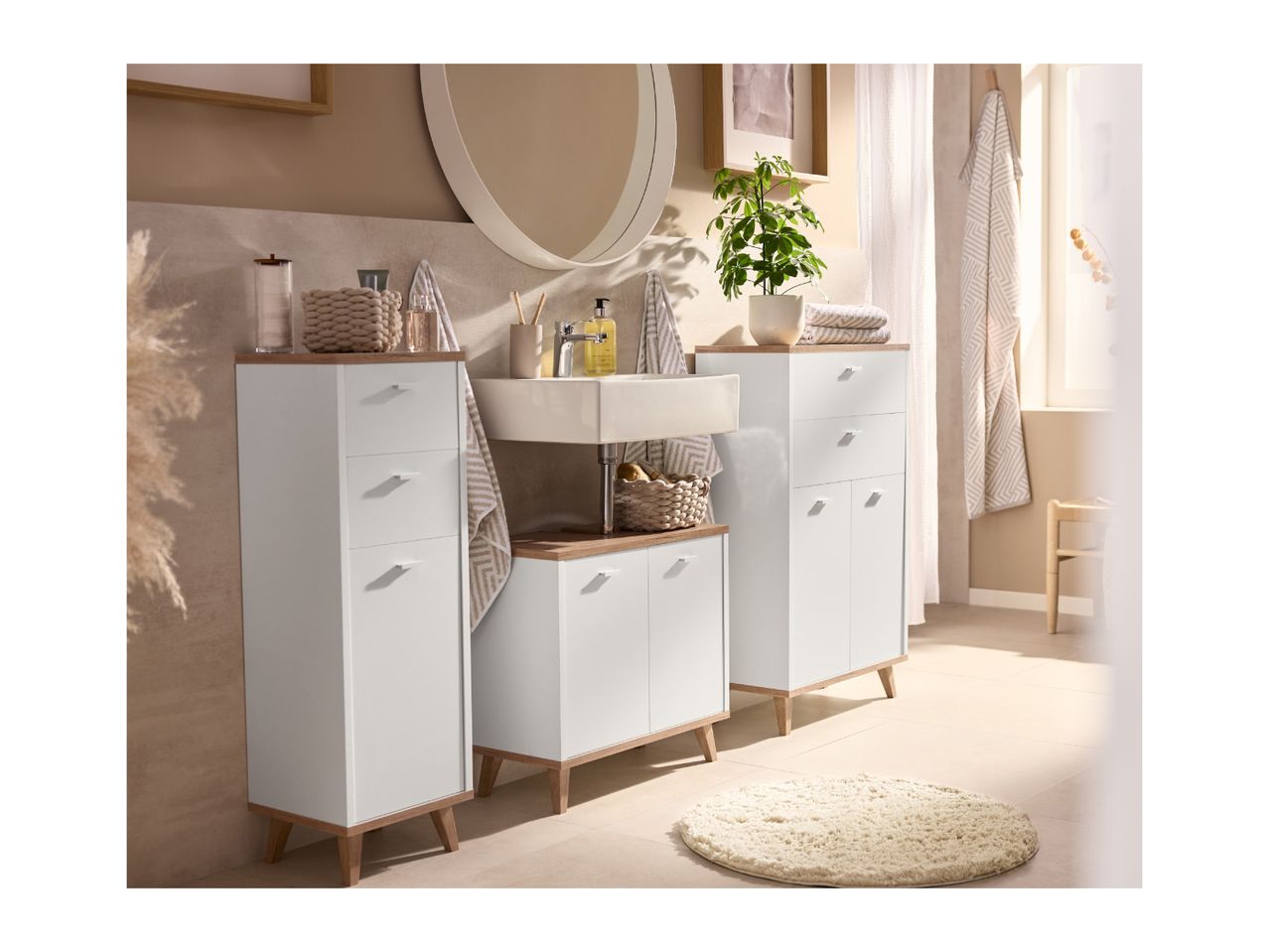 Bathroom with white and wood-effect furniture, including tall cabinets and a vanity with a sink.