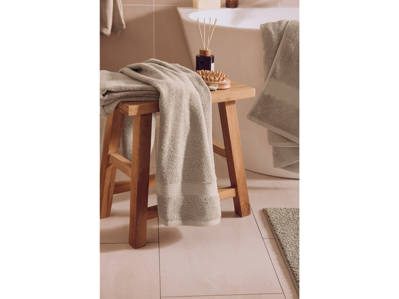 LIVARNO grey terry towels on a wooden stool in a bathroom.