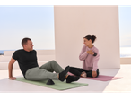 Man and woman on CRIVIT yoga mats, doing relaxation exercises outdoors.