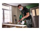 Man in safety gear spray painting a wooden board with a Parkside paint sprayer.