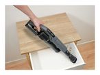 Handheld vacuum cleaner being used to clean dirt from an open drawer