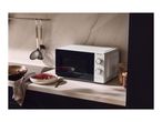 A white microwave on a kitchen countertop next to a bowl of soup