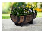 Barrel-shaped planter with purple pansies and yellow chrysanthemums on a concrete surface.