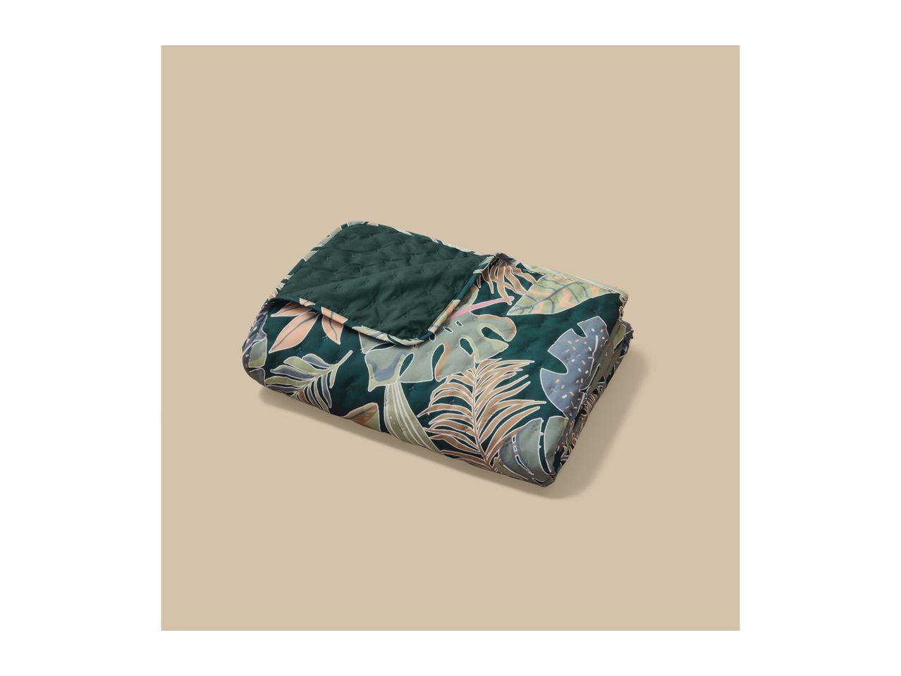 Quilted blanket with a tropical leaf pattern in shades of green, brown, and pink.