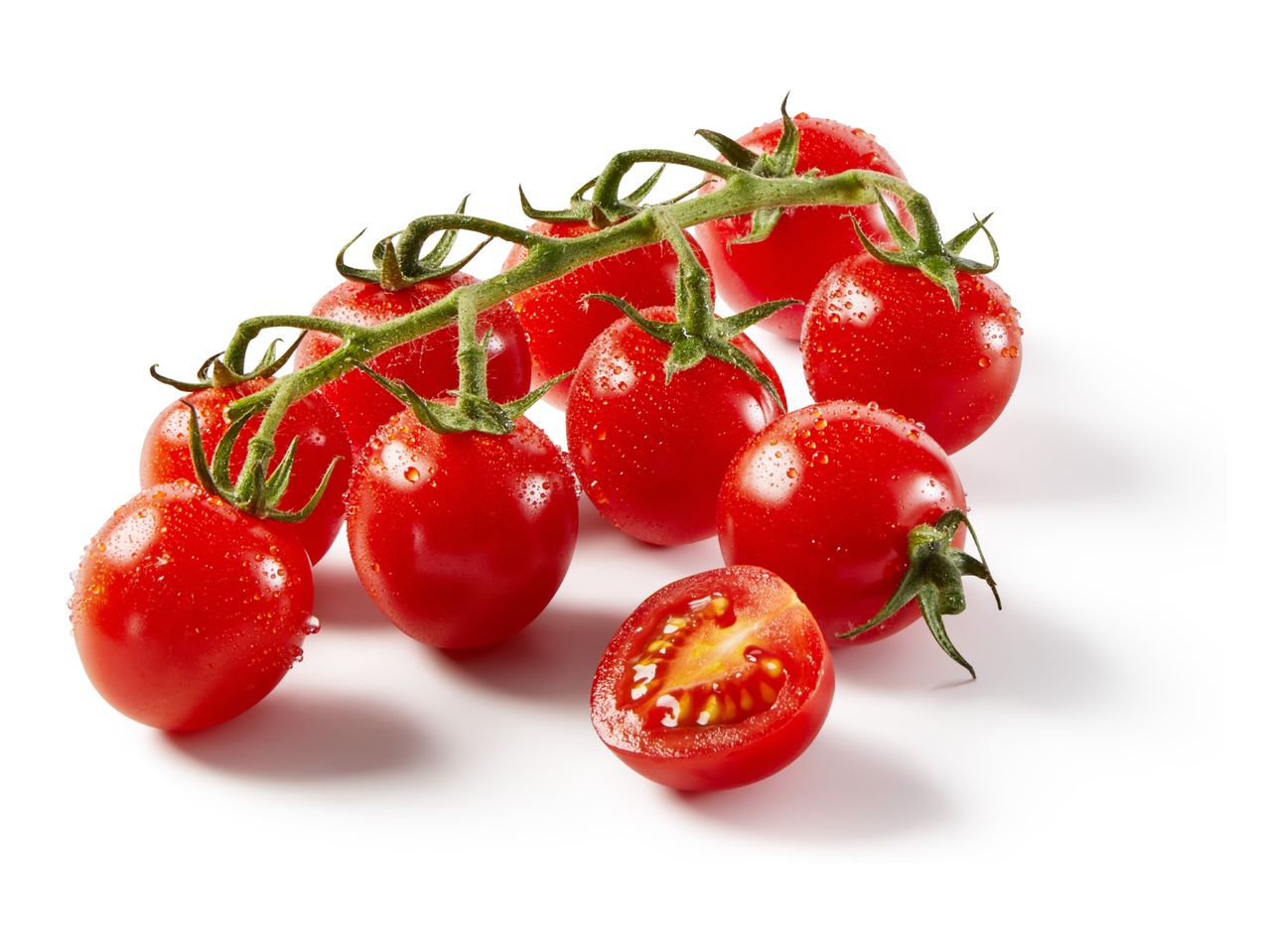 Fresh cherry tomatoes on the vine with water droplets, one cut in half, on a white background.
