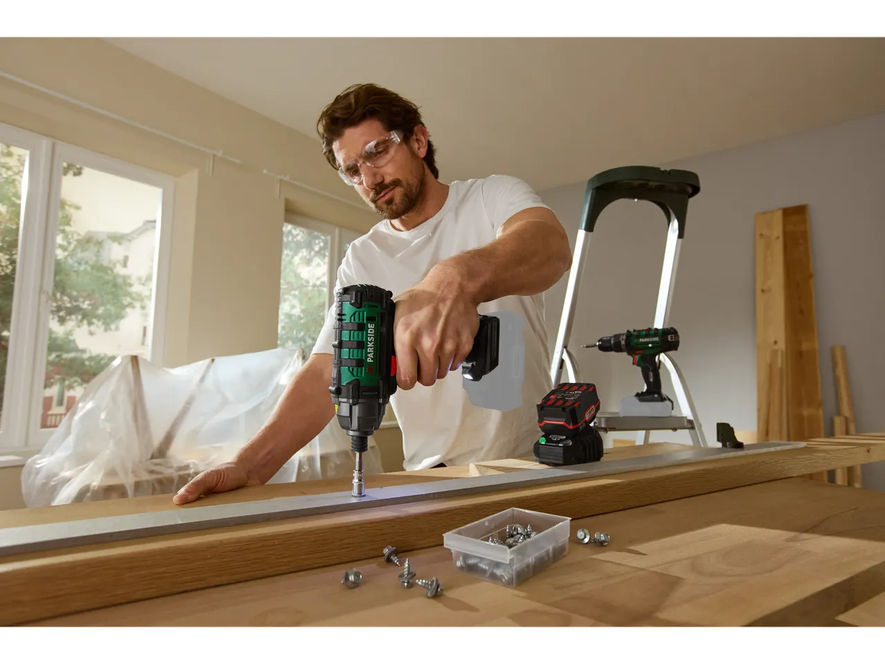 Man using a PARKSIDE® 20V Cordless Impact Driver on a wooden board.