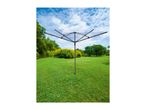 Rotary clothesline in a green garden with trees and a blue sky.