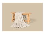 A soft beige fleece blanket draped over a rustic wooden bench.