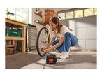 Woman inflating a bicycle tire with a portable air compressor in a garage.