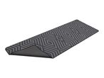 Grey runner rug with a geometric diamond pattern, partially curled to show the underside.