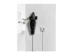 Black handheld vacuum cleaner charging on a white wall next to an electrical outlet.