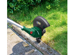 Cordless grass trimmer edging a lawn next to a concrete path.