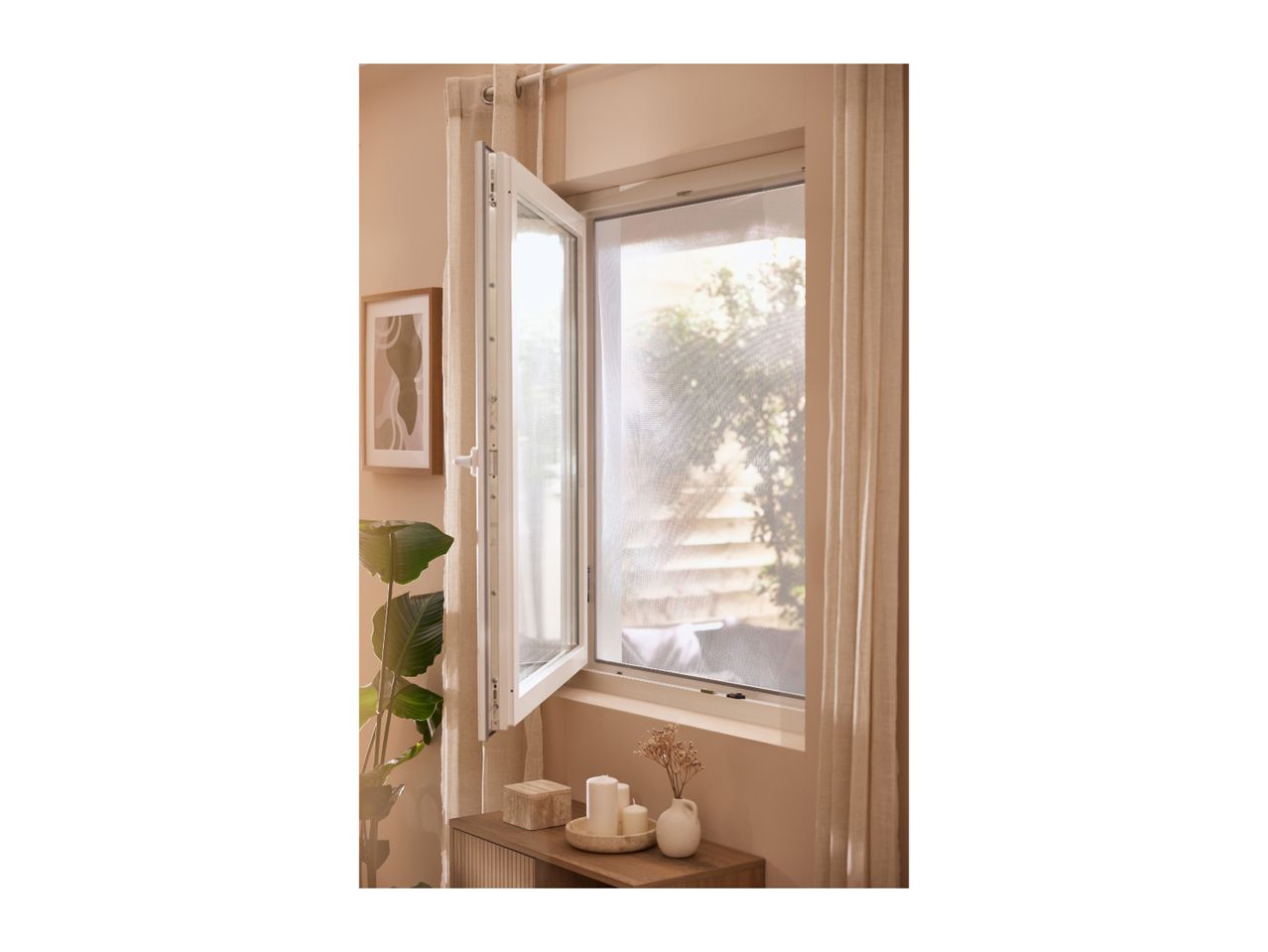 Open window with a mosquito net, light curtains, and a wooden side table with candles.