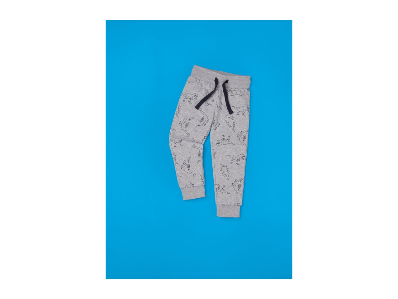 Grey children's sweatpants with dinosaur print and dark blue drawstring on a blue background.
