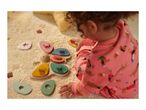 Child playing with a wooden butterfly shape sorter on a cream rug.
