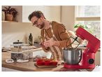 Man baking muffins with a red stand mixer and ingredients on a kitchen counter.