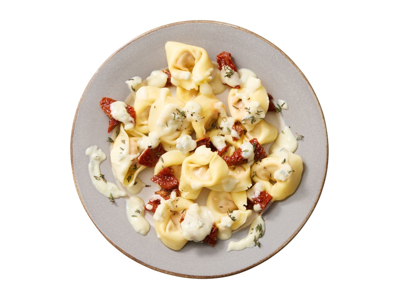 Tortellini with creamy sauce, sun-dried tomatoes, and herbs on a grey plate.