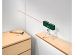 Um nível a laser Parkside verde em um tripé, com um feixe de laser vermelho na parede.