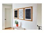 Three framed black and white tribal art prints hanging on a wall above a bench.