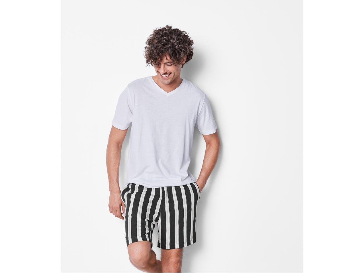 Bărbat cu tricou alb și pantaloni scurți cu dungi.