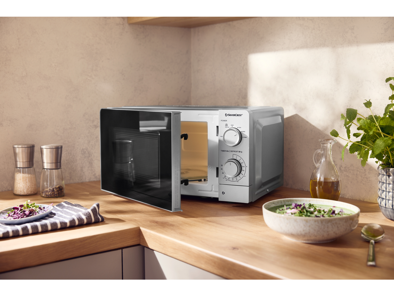 Micro-ondas SILVERCREST na bancada da cozinha, aberto, com configurações de cozedura visíveis.