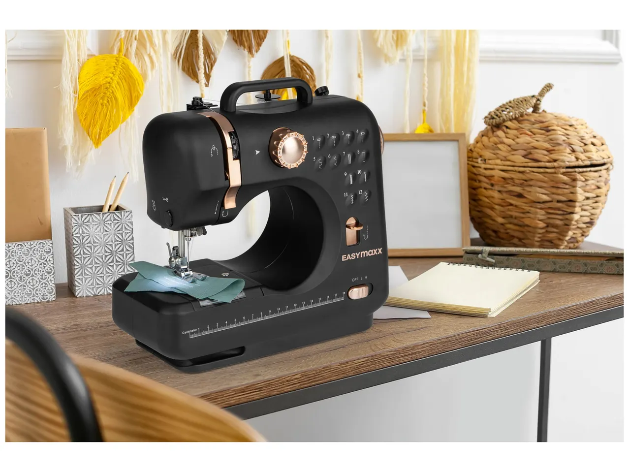 Une machine à coudre Easymaxx noire et rose gold est posée sur un bureau.