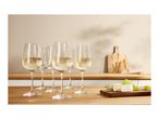 White wine glasses with wine, cheese, grapes, and breadsticks on a wooden counter.