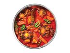 Oxtail stew with vegetables, bay leaf, and green peppers in a metal pot.