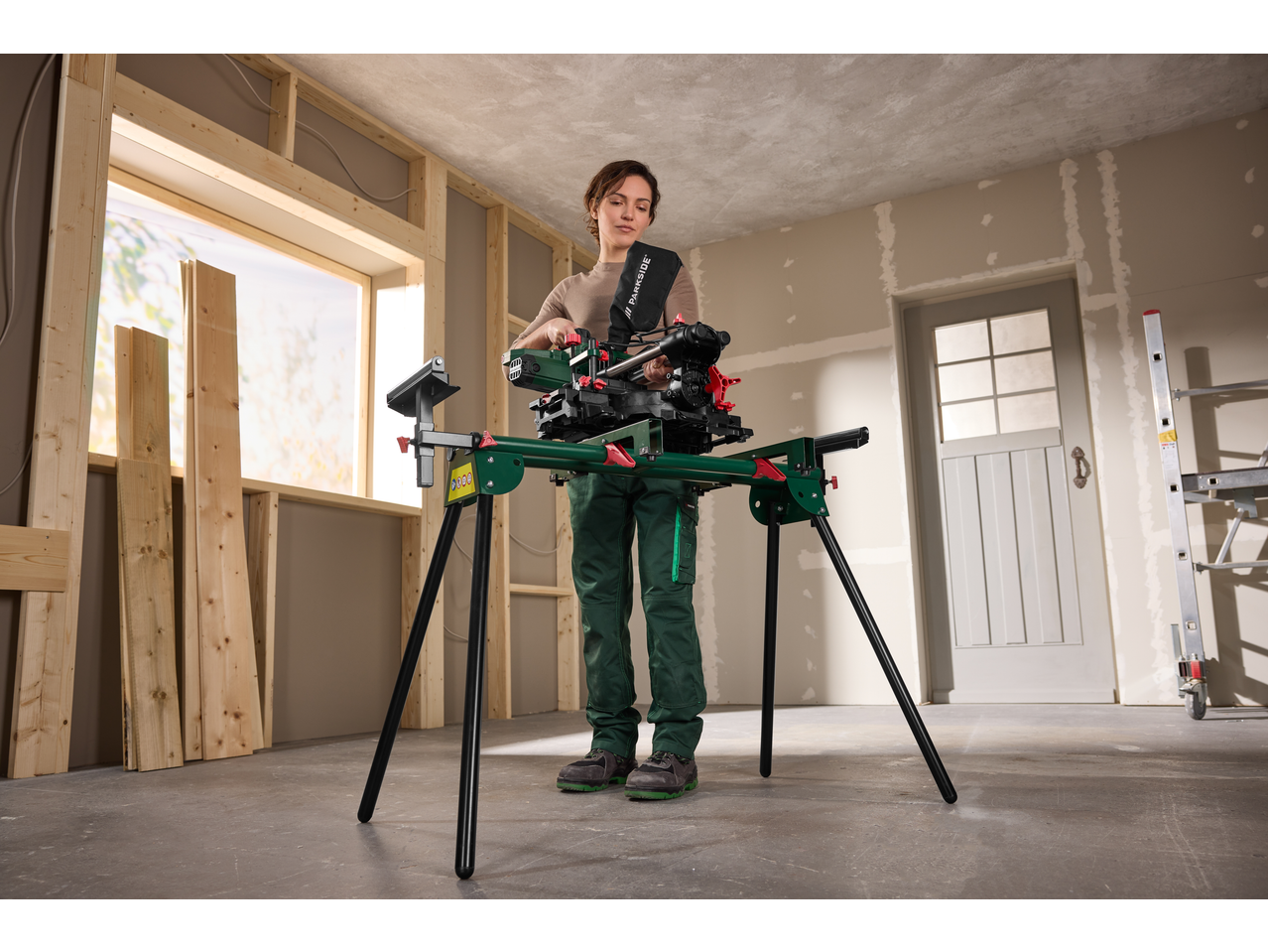 Femeie utilizând suportul universal pentru mașini PARKSIDE cu fierăstrău pe un șantier.