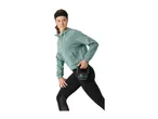 Woman in a green hoodie and black leggings holding a kettlebell, exercising.