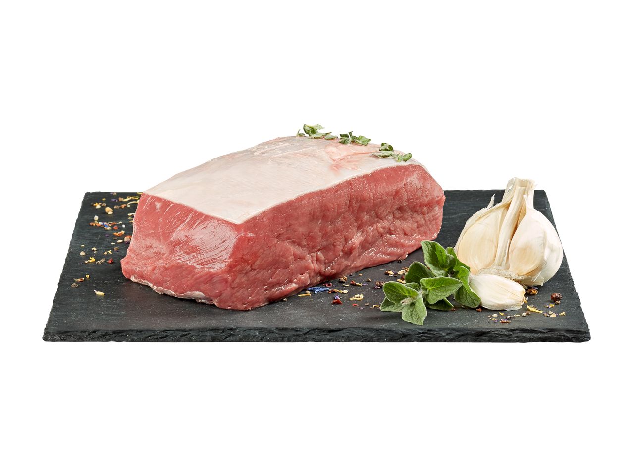Un pezzo di carne cruda su un tagliere di ardesia con aglio e spezie.