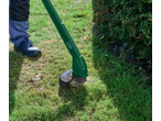 Trimmer de gazon PARKSIDE în acțiune, tăind iarba lângă un tufiș.