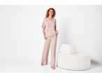 Woman in a light pink loungewear set, standing next to a white round armchair.