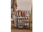 A black metal shoe rack with various shoes, a jacket, and a plant in a pot.