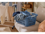 Blue W5® 40 l laundry basket with jeans on a beige sofa, clothes drying rack in the background.