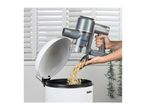 Handheld vacuum cleaner emptying crumbs into a white bin with a lid.