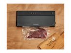 A black vacuum sealer packaging a piece of meat on a wooden surface.