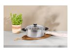 Stainless steel pot with a glass lid on a wooden board, next to a basil plant.