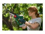 A woman wearing safety glasses and gloves uses a cordless mini chainsaw to prune a tree branch.