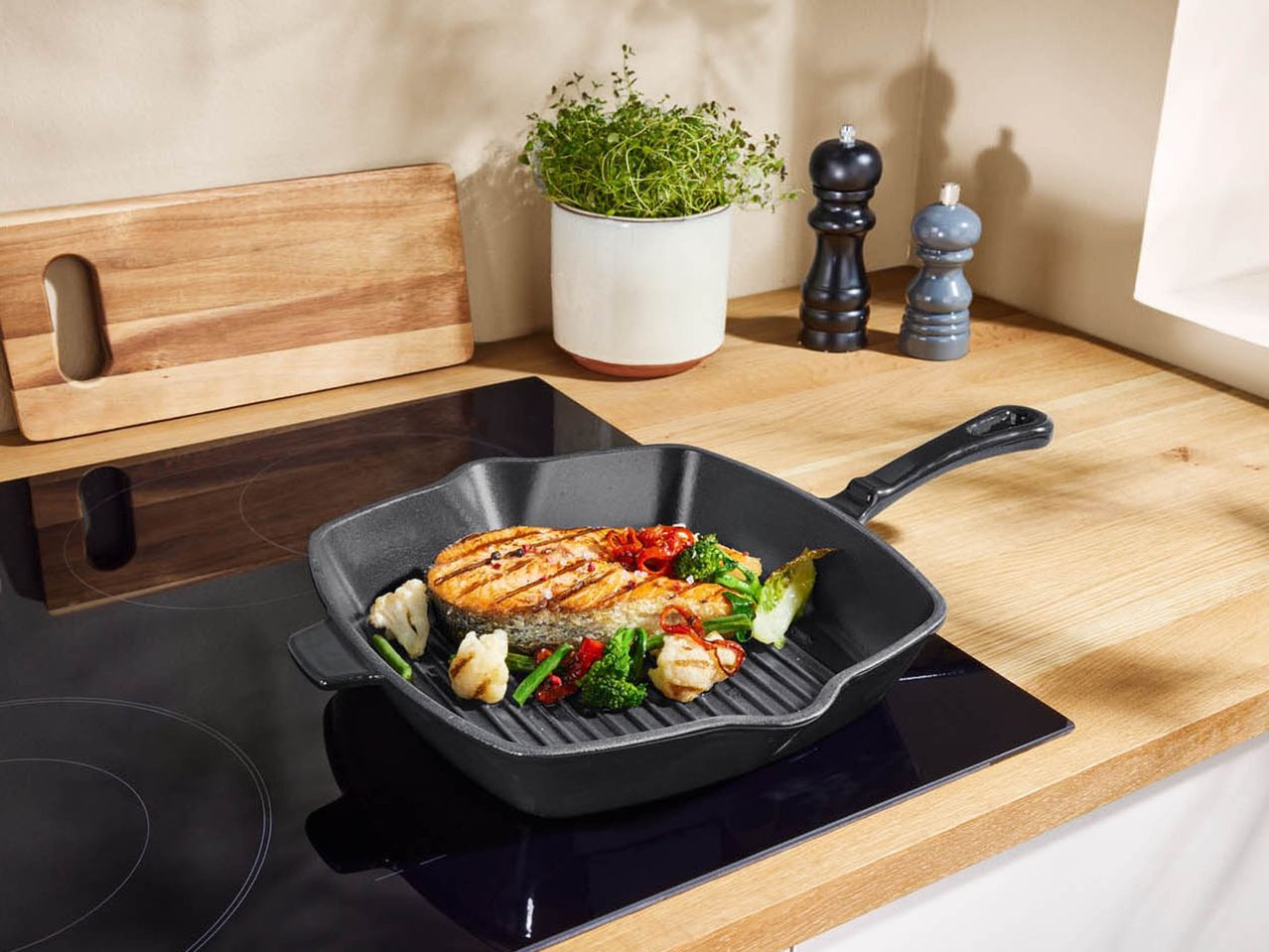 Grilled salmon and vegetables in a cast iron pan on a kitchen counter.