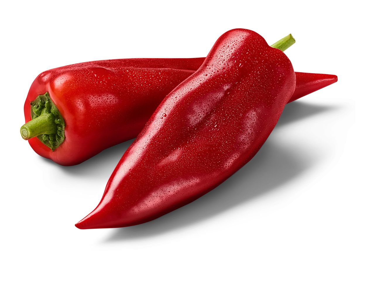 Two fresh red pointed peppers with water droplets, casting a shadow on a white background.