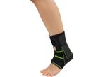 A person's leg and foot wearing a black and green ankle brace.