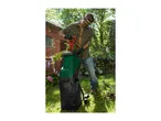 Man in safety goggles and gloves using a garden shredder to process branches.