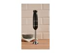 Black hand blender with '1973' text on a wooden countertop in front of a tiled wall.