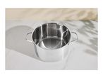 Stainless steel cooking pot with measurement markings on a white marble surface with shadows