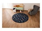 A child's room with a space-themed rug, astronaut plushie, and a grey armchair.