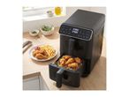 Black dual-basket air fryer on a wooden counter with fried chicken and fries.